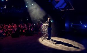 Over ons. Schrijver geeft voordracht voor publiek op Wintertuinfestival in Nijmegen