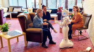 Oudere en twee begeleiders in gesprek met een robot voor Robotstories.